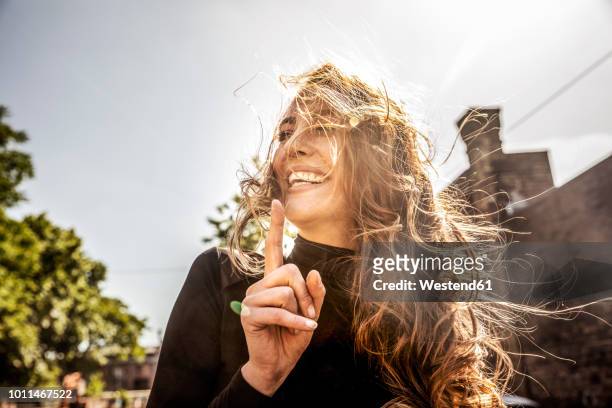portrait of laughing woman with blowing hair - 人差し指 女性 ストックフォトと画像