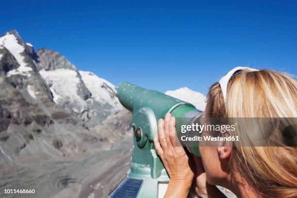 austria, carinthia, woman looking through binocular pointing at grossglockner peak and pasterze glacier, view from kaiser-franz-josefs-hoehe - grossglockner fotografías e imágenes de stock