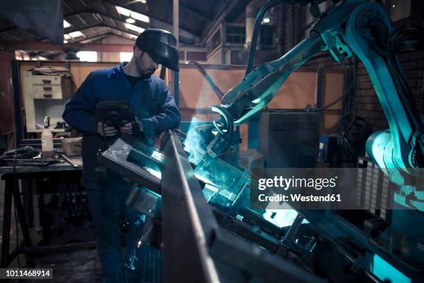 welder welding metal with robot - human robot stock pictures, royalty-free photos & images