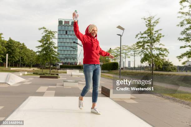 carefree senior woman wearing red hoodie outdoors - senior women dancing stock pictures, royalty-free photos & images