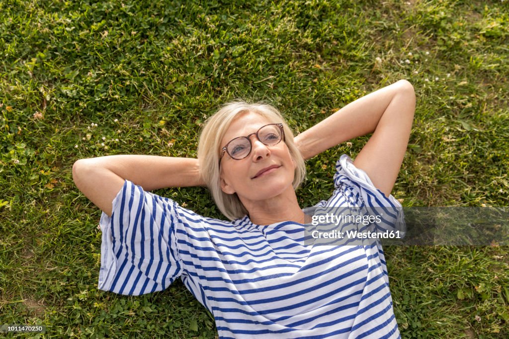 Portrait of smiling senior woman lying in grass