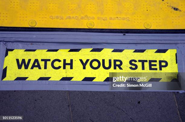 'watch your step' sign taped next to a plastic safety ramp on the sidewalk of a city street - trip hazard stock pictures, royalty-free photos & images