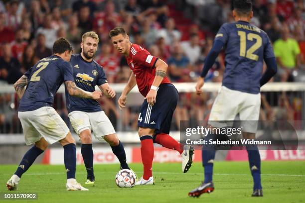 Niklas Suele of Bayern Muenchen passes the ball as Victor Lindelof and Luke Shaw of Manchester watch during the friendly match between Bayern...