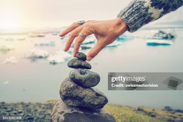 detalhe da pessoa empilhando rochas na lagoa de geleira na islândia - rocha equilibrada - fotografias e filmes do acervo