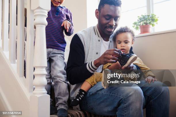 father putting shoes on baby son - man putting on shoes at home fotografías e imágenes de stock