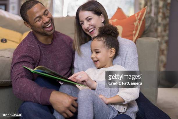 gemengd ras familie samen met het lezen van een boek - funny fat women stockfoto's en -beelden