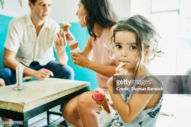 Portrait of young girl enjoying ice cream with family in ice cream shop