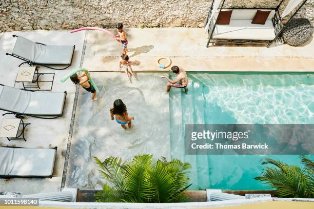 overhead view of family getting into swimming pool in courtyard of boutique hotel - hot mexican girls stock pictures, royalty-free photos & images