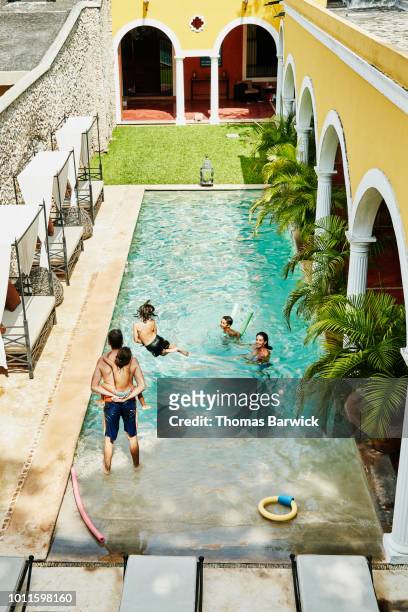 family playing together in pool in courtyard of boutique hotel - hot mexican girls stock-fotos und bilder