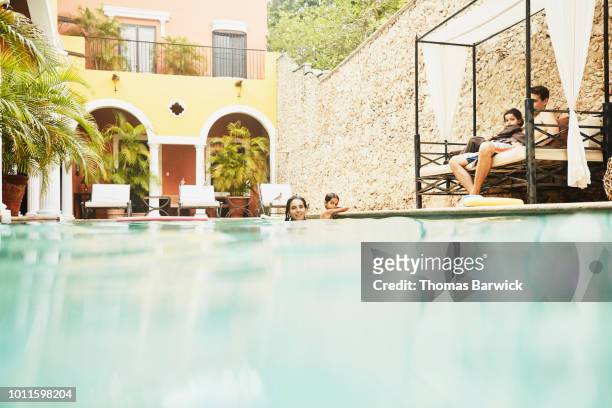 family hanging out together at pool in courtyard of boutique hotel - hot mexican girls stock pictures, royalty-free photos & images