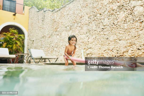 young girl playing with pool toy while hanging out with family in pool at tropical resort - hot mexican girls stock pictures, royalty-free photos & images