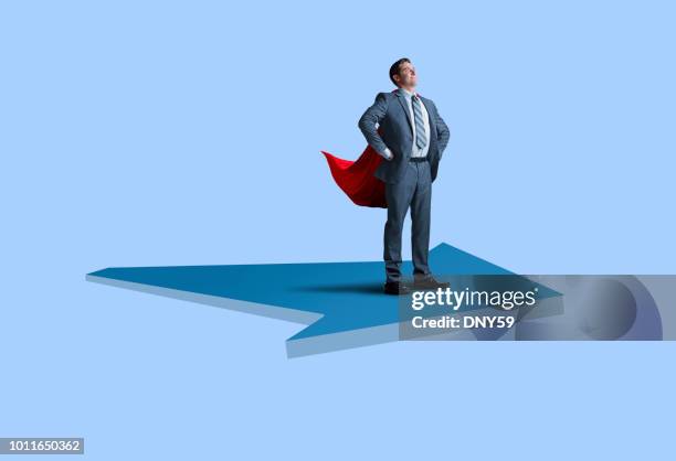 businessman super hero with cape rides large arrow on blue background - man with arrow stock pictures, royalty-free photos & images