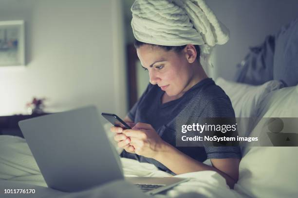 mujeres jóvenes que trabajan de tarde en casa usando laptop - cabello mojado fotografías e imágenes de stock