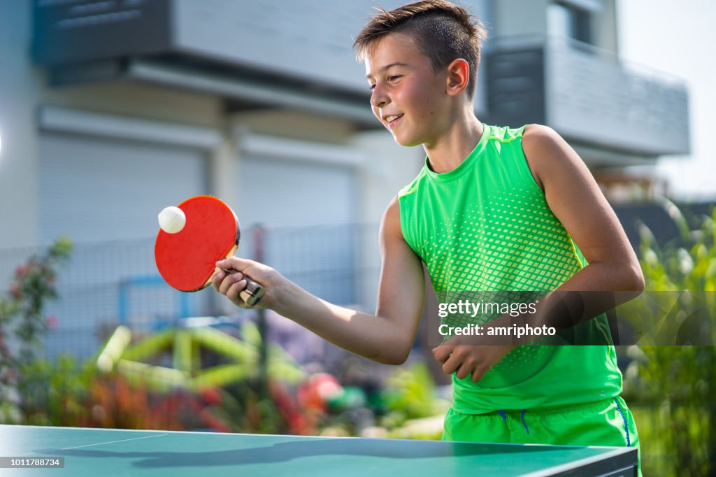 Smiling boy playing table tennis in garden