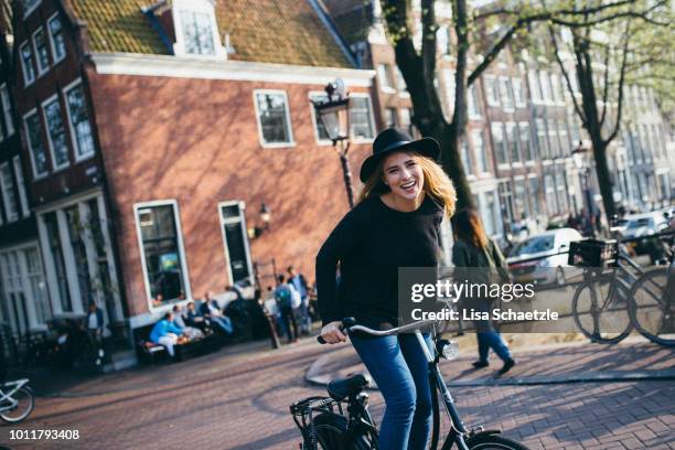 woman riding her bike trough amsterdam - amsterdam autumn stock pictures, royalty-free photos & images