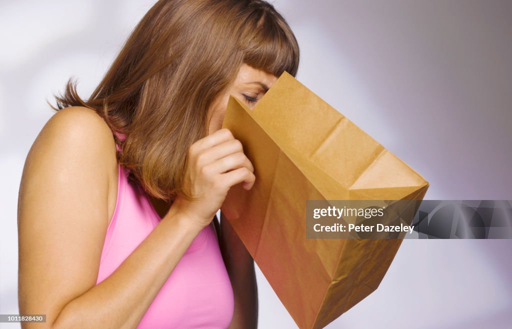 Woman vomiting into paperbag
