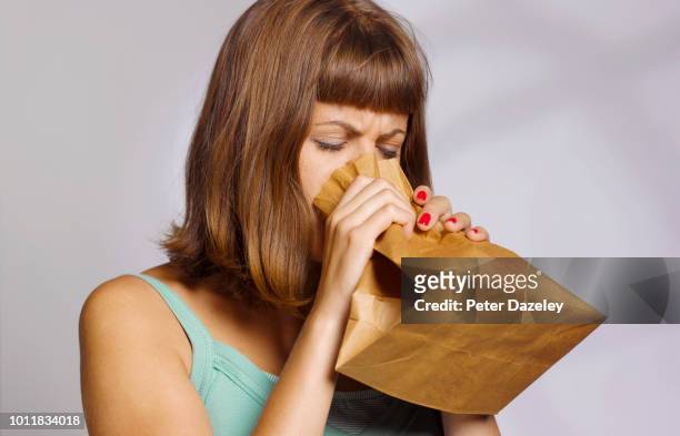 woman hyperventilating into paperbag - breathing problems stock pictures, royalty-free photos & images