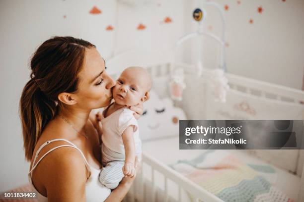 tenant tendrement sa petite fille nouveau-née - chambre nouveau né famille photos et images de collection