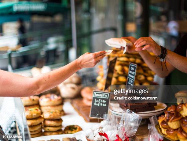 customer paying for sweet pastry using cash at food market - banca de feira imagens e fotografias de stock