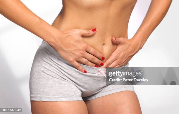 women massaging her painful stomach - ets fotografías e imágenes de stock