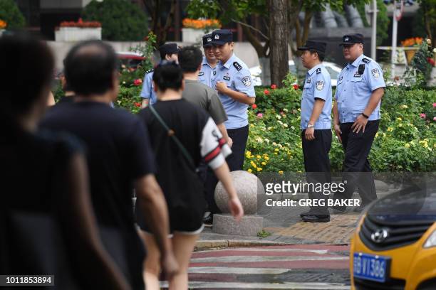 Police wait to check the identification of passersby as they search for petitioners near China's Banking Regulatory Commission in Beijing on August...