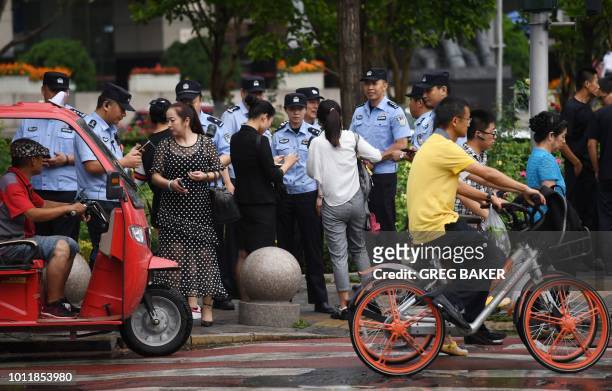 Police check the identification of passersby as they search for petitioners near China's Banking Regulatory Commission in Beijing on August 6, 2018 -...