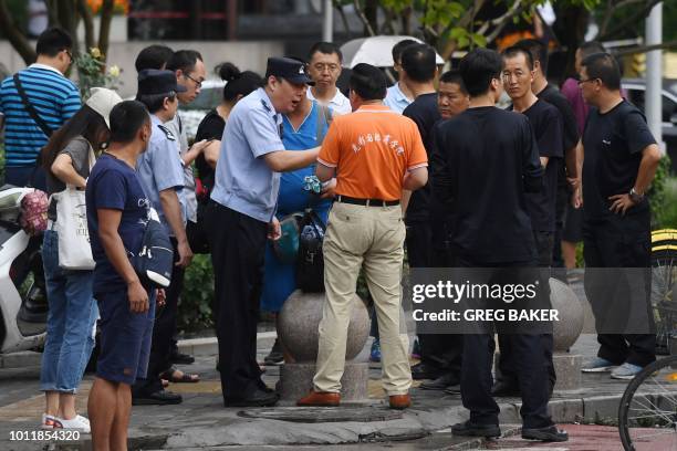 Police officer speaks with a petitioner as security personnel look on opposite China's Banking Regulatory Commission in Beijing on August 6, 2018. -...