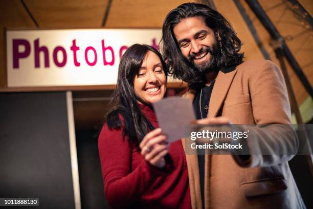 couple admiring a photo booth picture - photo booth couple stock pictures, royalty-free photos & images