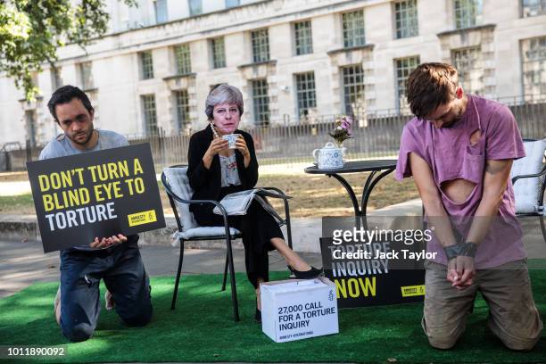 Activists from Amnesty International posing as British Prime Minister Theresa May and victims of torture hold a demonstration on Whitehall outside...