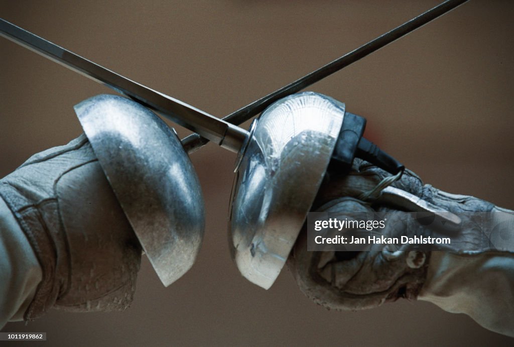Two Fencers Holding Fencing Foils In Confrontation