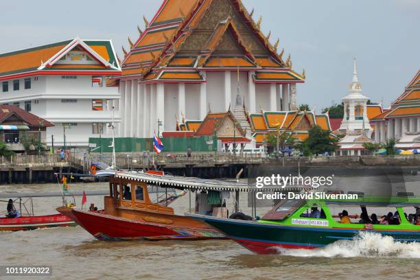 Water taxis and ferry boats pass the Wat Arun Buddhist shrine, the Temple of Dawn, on the Thonburi west bank of the Chao Phraya River on July 27,...