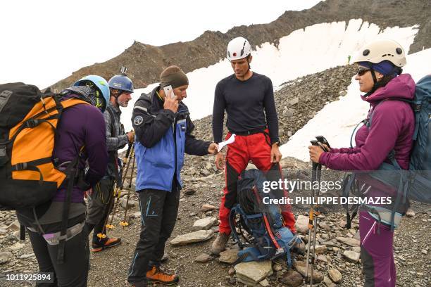 French gendarme by phone checks the reservation at the 'Refuge du Gouter' of a group of mountaineers on August 6, 2018 near Saint-Gervais, below the...