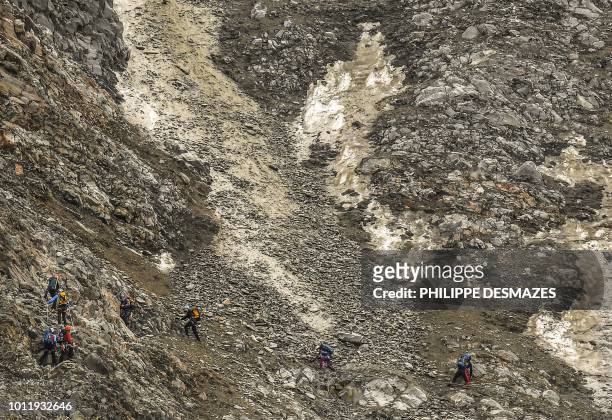 Mountainees try to cross a dangerous corridor while rocks falling as they take the famous 'Couloir du Gouter' on the 'Voie Royale' route to climb...