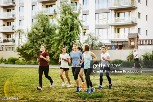 group of women jogging together - laufen und gras und sport stock-fotos und bilder