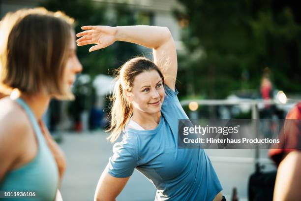 women warming up outside together - active woman fotografías e imágenes de stock