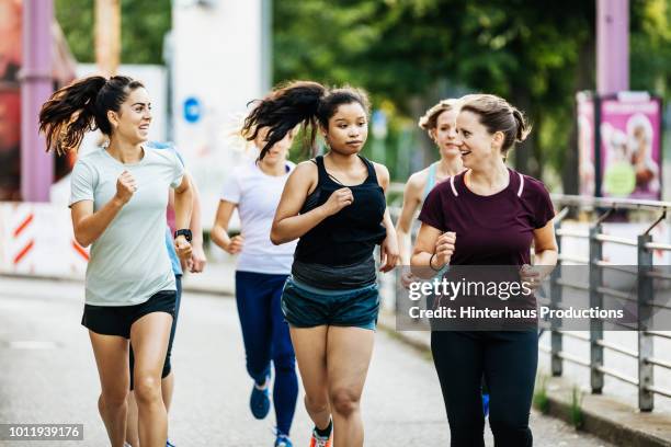 women's fitness group running through the city - レギンス　 ストックフォトと画像