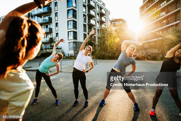 urban fitness group warming up for run - sport stock-fotos und bilder