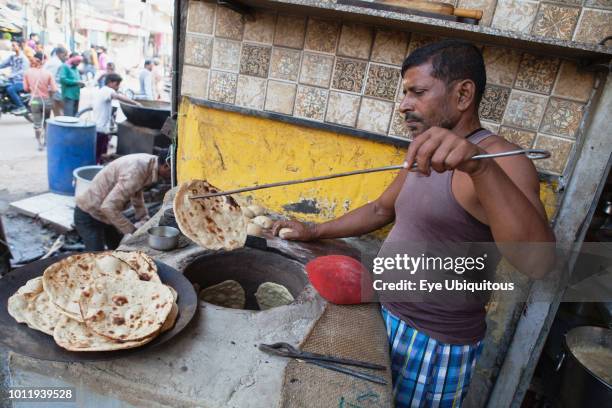 India, Uttar Pradesh, Varanasi, A cook making tandoori roti at a food hotel.