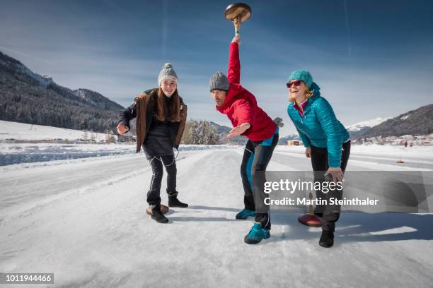 familie beim eisstock schießen auf zugefrorener see eisfläche - curling stock-fotos und bilder