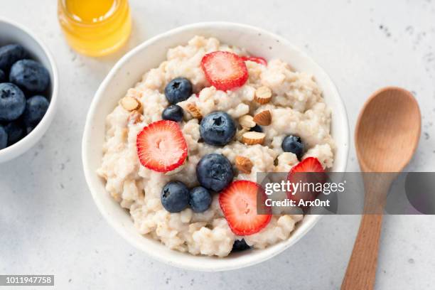 oatmeal porridge with fresh berries in a bowl - rolled oats stock-fotos und bilder