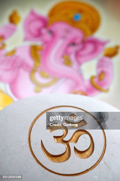 The Om or Aum symbol of Hinduism and Buddhism on a white stone. Image of Ganesha also known as Ganapati on a tablet.