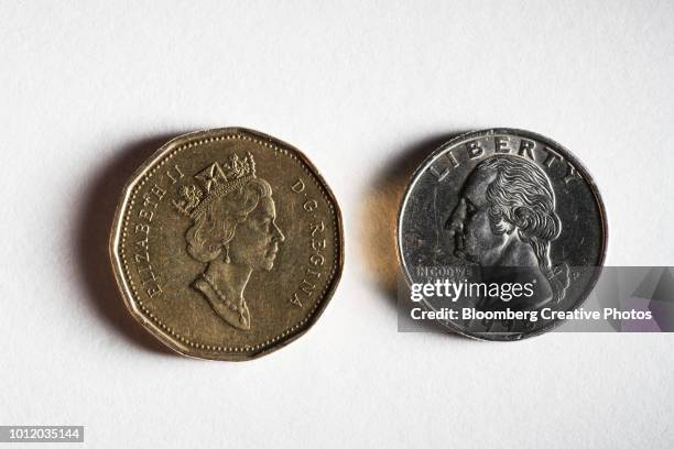 a canadian one dollar coin and a u.s. twenty-five cent coin - twenty five cent coin stockfoto's en -beelden