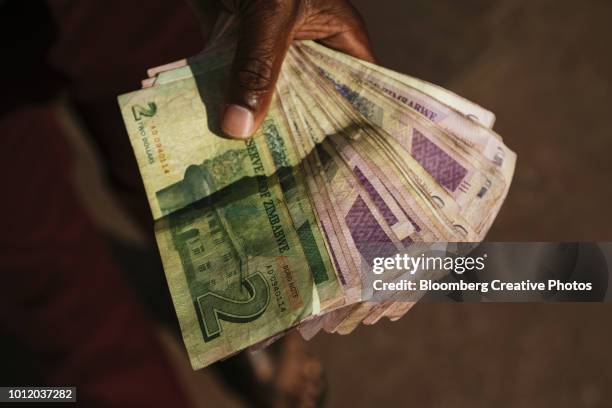 a man holds zimbabwean dollar bond banknotes - zimbabwe dollar stock pictures, royalty-free photos & images