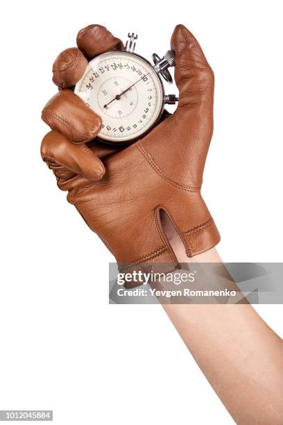 close up of hand holding stopwatch on white background - leather glove stockfoto's en -beelden