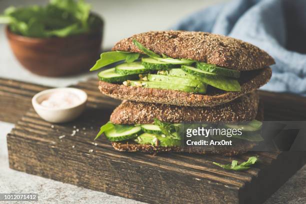vegan rye sandwich with avocado and cucumber - bean sprout stock-fotos und bilder