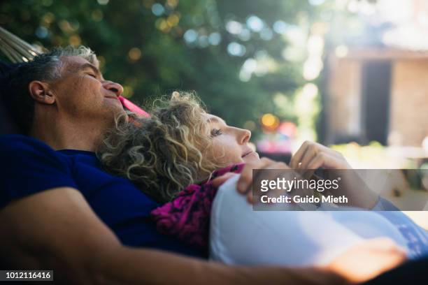 mature couple having a nap in a hammock. - woman 45 sleeping stock-fotos und bilder