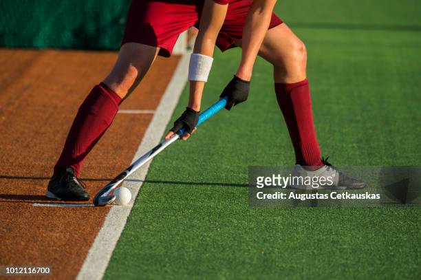 low section of player playing hockey on field - hockey player stockfoto's en -beelden