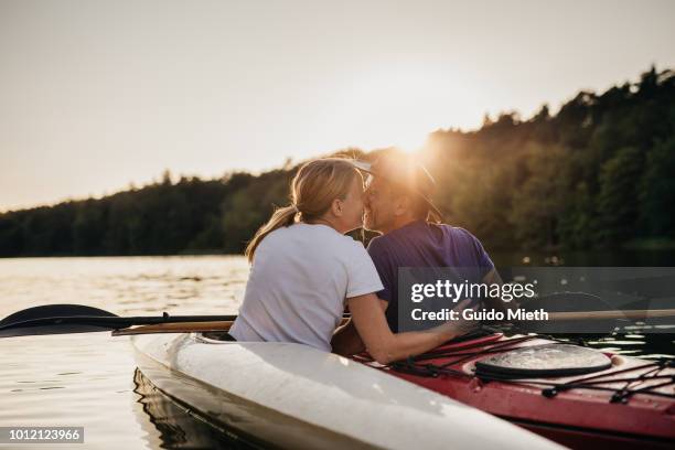couple in love kissing in sunset on a lake. - two people canoeing on a lake stock pictures, royalty-free photos & images