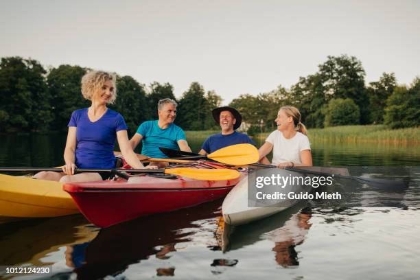 group of friends having fun in their canoes at a lake. - seniors canoeing stock pictures, royalty-free photos & images