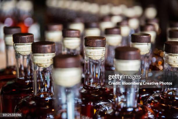 bottles of aged rum sit on a table prior to labeling - distillery 個照片及圖片檔